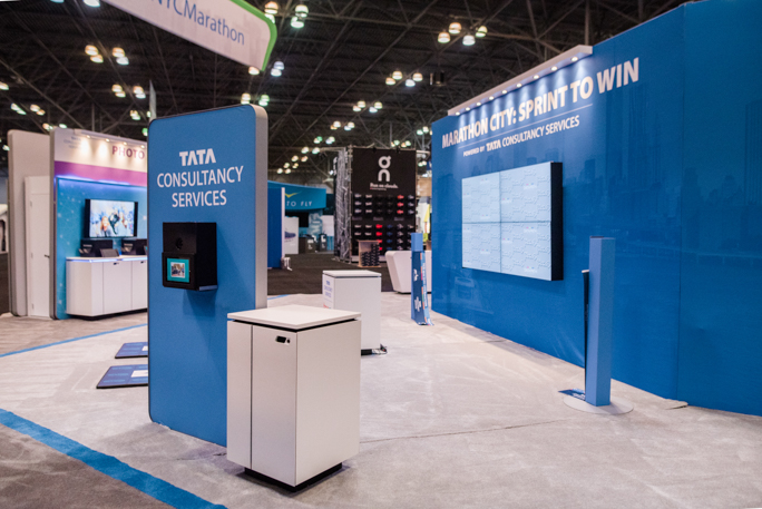 blue expo booth with a screen and a table