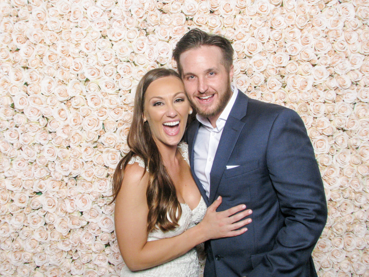 couple smiling next to a flower backdrop