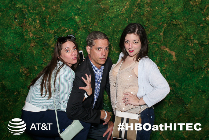 Three people posing next to a green backdrop