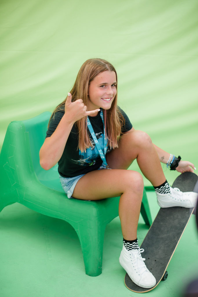 A girl posing for a photo next to green background