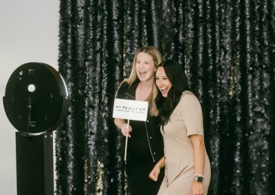 Two women smiling holding a prop