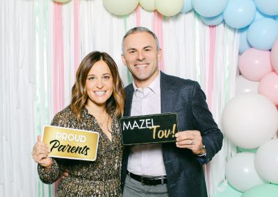 Parents holding Proud Parents and Mazel Tov signs in a photo booth at a Minneapolis bar mitzvah