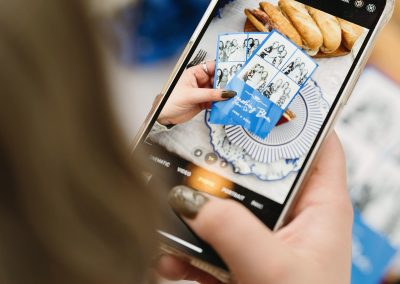 Wedding guest photographing her photo booth strips with a phone to share them on social media
