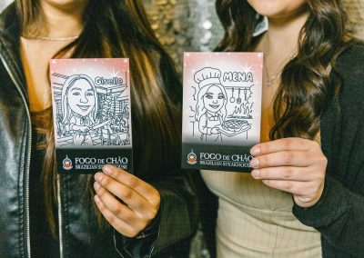 Two guests holding branded Sketch Bot caricature keepsakes drawn live at their event