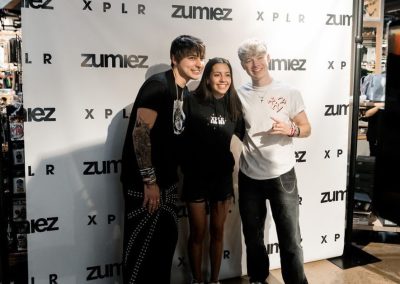 Three teens posing together in front of a branded photo booth backdrop at a party in Minneapolis