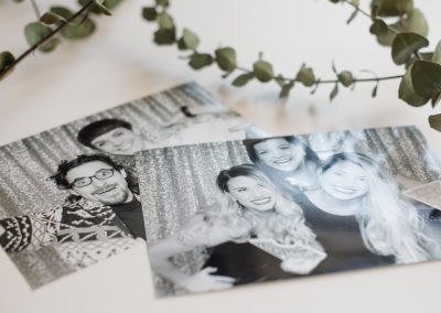 Black and white photo booth prints from a holiday party laid out with eucalyptus