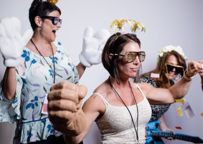 Guests in oversized gloves and novelty sunglasses posing at a corporate event photo booth in Minneapolis