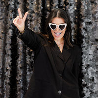 Guest in heart sunglasses at an open style photo booth with sequin backdrop and on-site attendant
