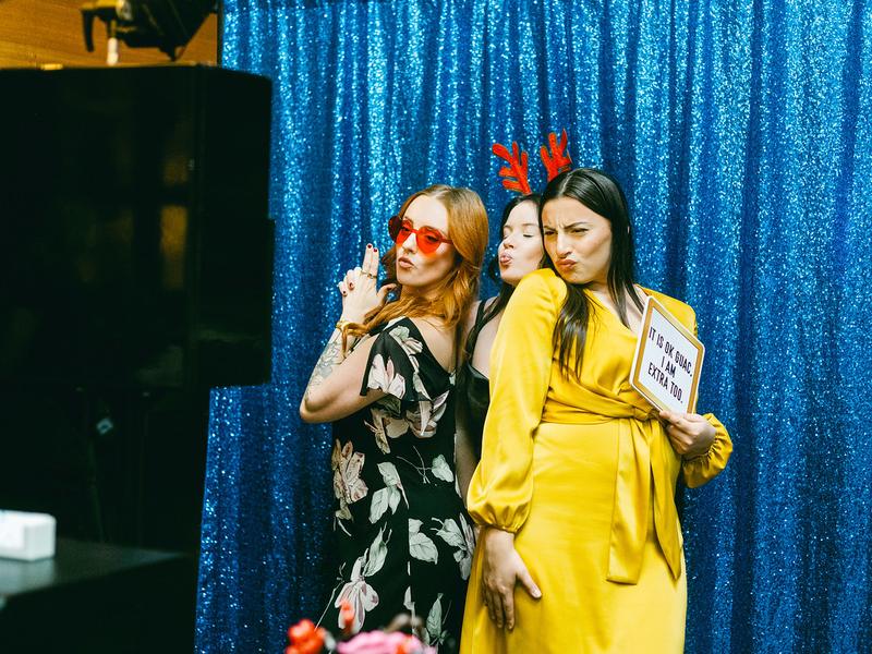 Three guests posing in front of a blue sequin open style photo booth backdrop
