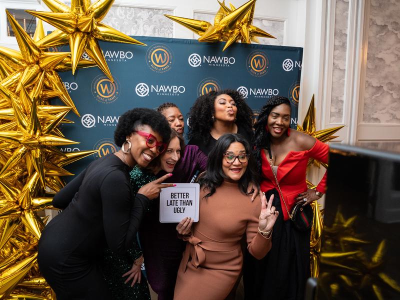 Guests posing at a branded corporate backdrop with an open style photo booth
