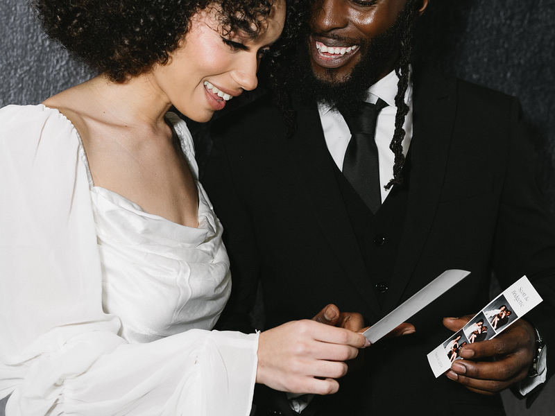 Bride and groom looking at their photo strip from an open style photo booth