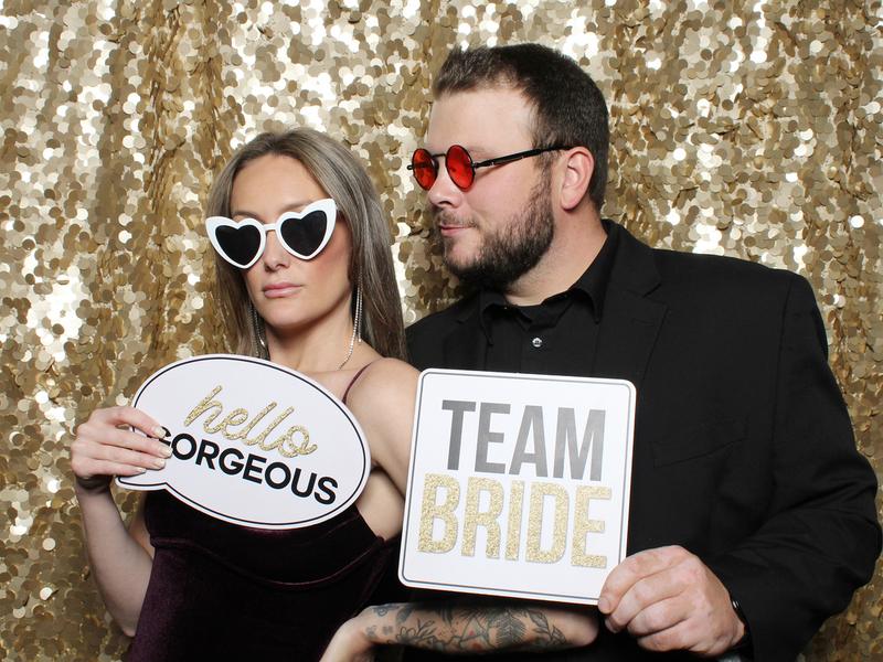 Bride and guest holding Team Bride props at an open style photo booth