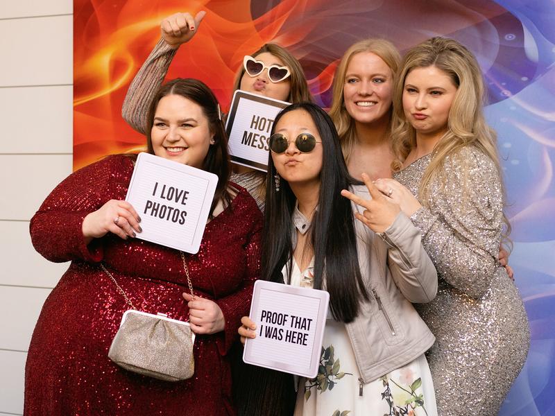 Group of guests holding sign props at an open style photo booth backdrop