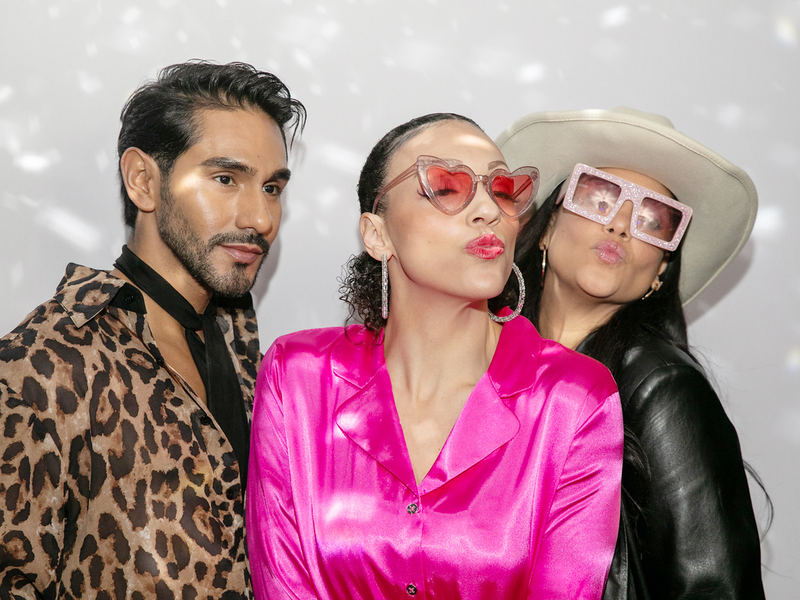 Three guests in heart sunglasses posing at an open style photo booth