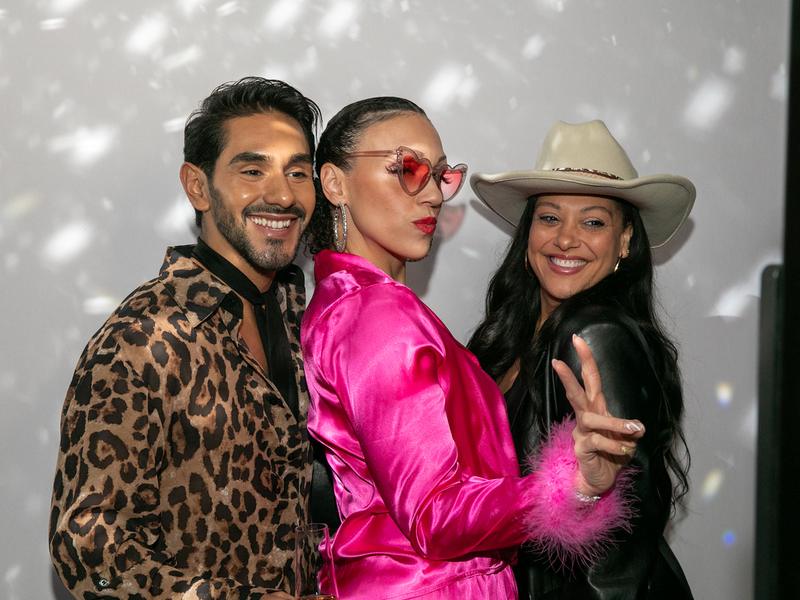 Party guests in sunglasses posing at an open style photo booth