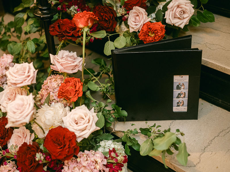 Photo strip guest book on a floral table at an open style photo booth