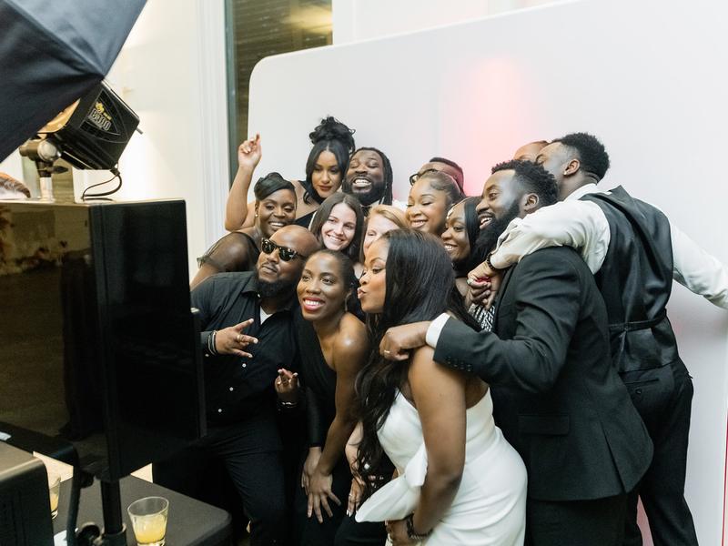 Wedding guests crowding into an open style photo booth group photo