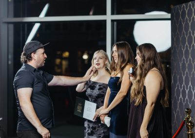 Photo booth attendant posing guests on a red carpet at a Minneapolis event