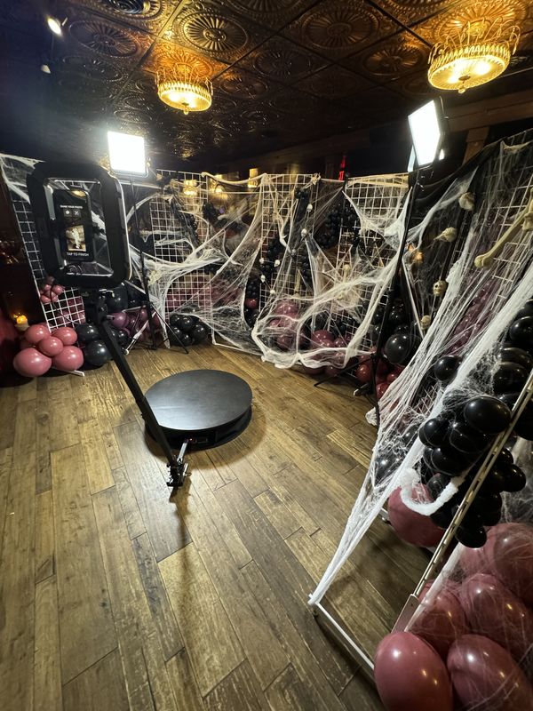 360 photo booth platform with spiderweb and balloon backdrop at a Halloween party