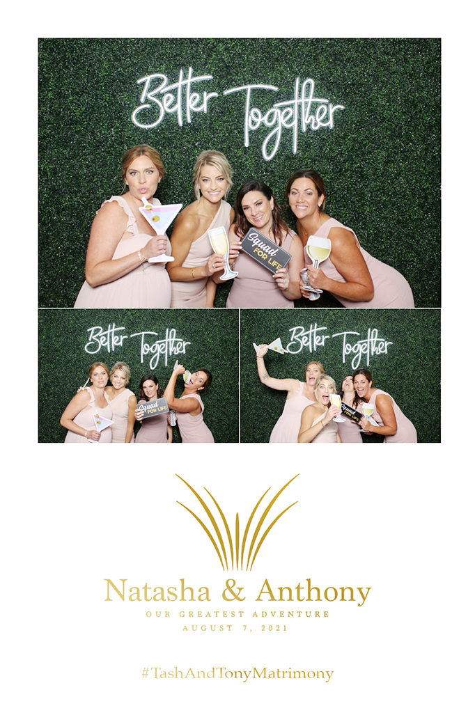 Wedding print of bridesmaids under a Better Together neon sign on a green hedge wall