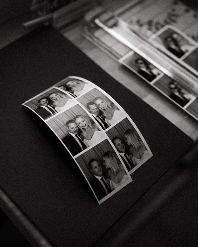 Black and white photo strips laid out on a table at an enclosed photo booth event