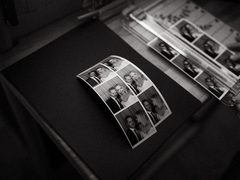 Black and white photo strips laid out on a table at an enclosed photo booth event