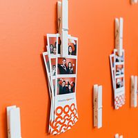 Branded photo strips clipped to an orange brand wall