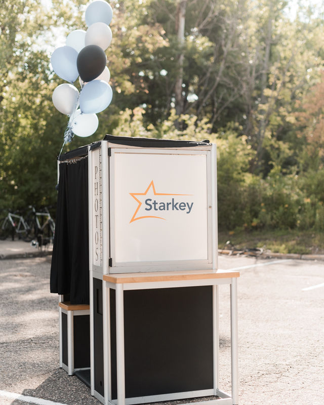 Branded enclosed photo booth with a company logo panel at an outdoor corporate event