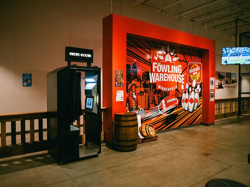 Branded enclosed photo booth next to a custom mural at an entertainment venue