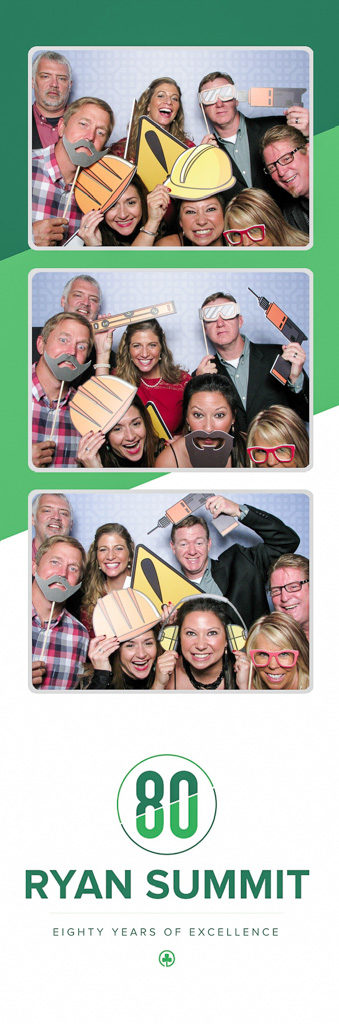 Corporate summit photo strip with coworkers wearing hard hat and mustache props, green 80 years logo