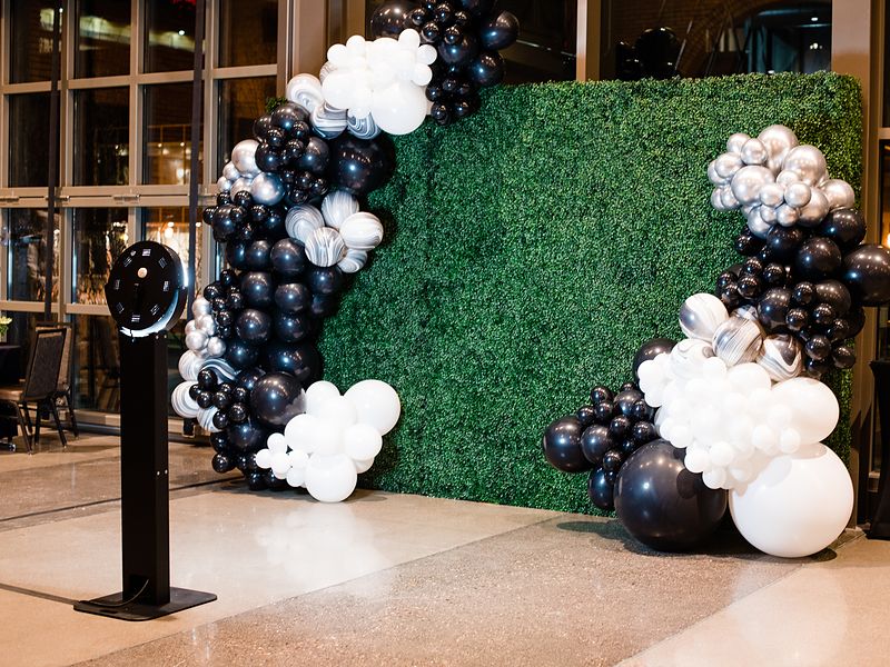 Boomerang booth in front of a greenery wall with black and white balloons at a corporate summit