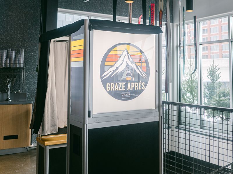 Enclosed photo booth with a custom logo panel at a brand event