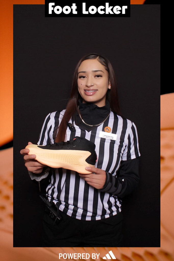 Foot Locker branded 4x6 print of an employee in a referee shirt holding a new sneaker