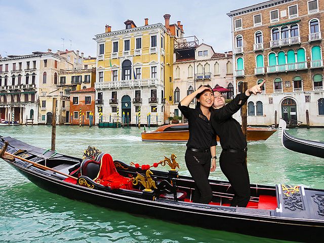 Two guests standing on a gondola in Venice, full body green screen photo
