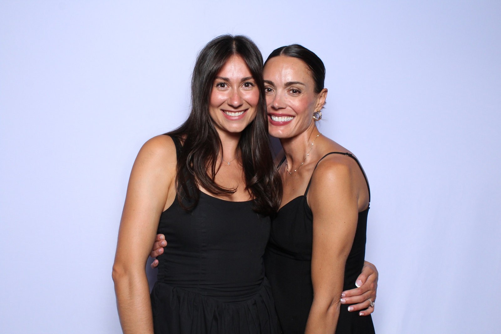 Two friends in black dresses straight from the camera in color, before glam retouching