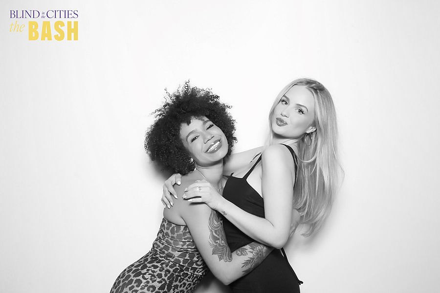 Two friends posing at a charity gala in a black and white glam photo booth