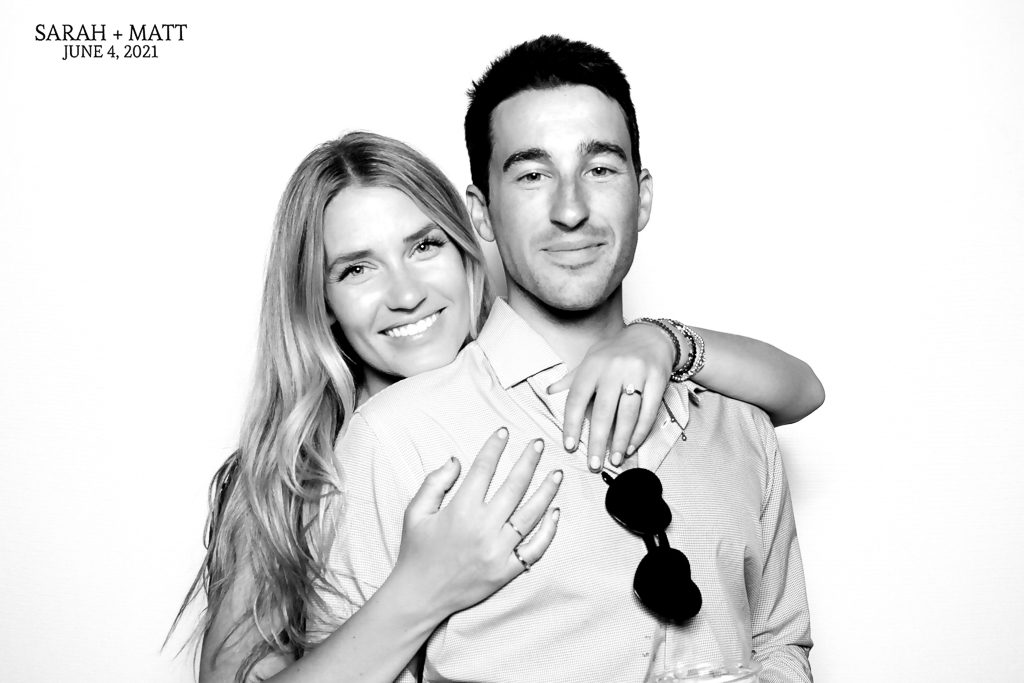 Engaged couple showing off a ring in a black and white glam photo booth portrait