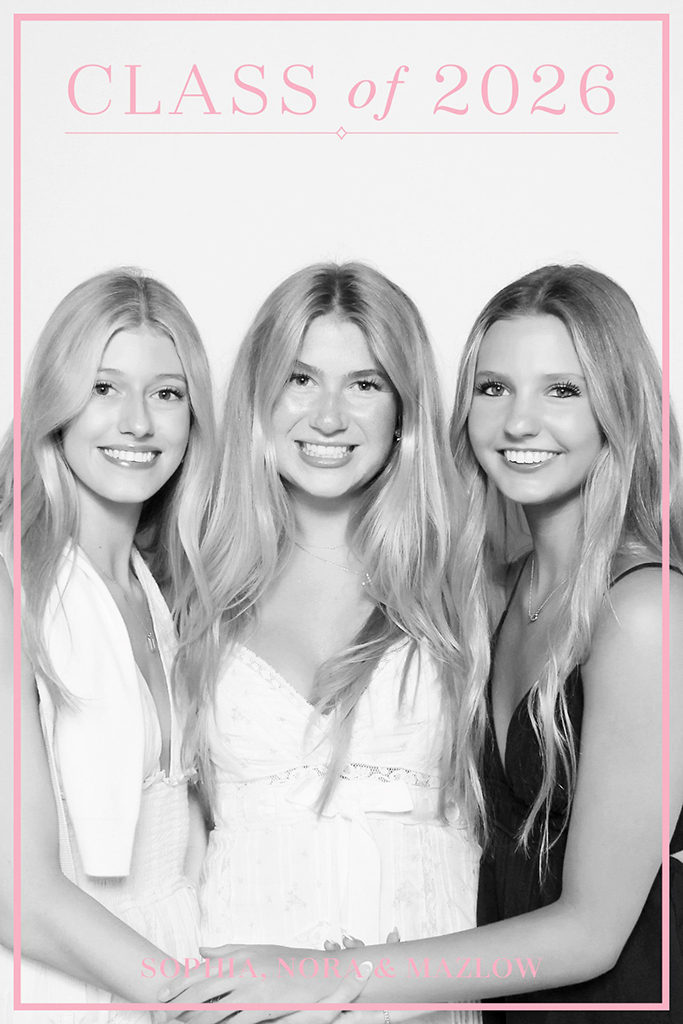 Three graduates smiling in a glam photo booth print with a pink Class of 2026 frame