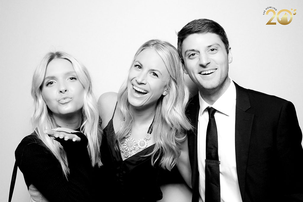 Three guests blowing kisses and smiling in a glam photo booth at a Roaring 20s themed party