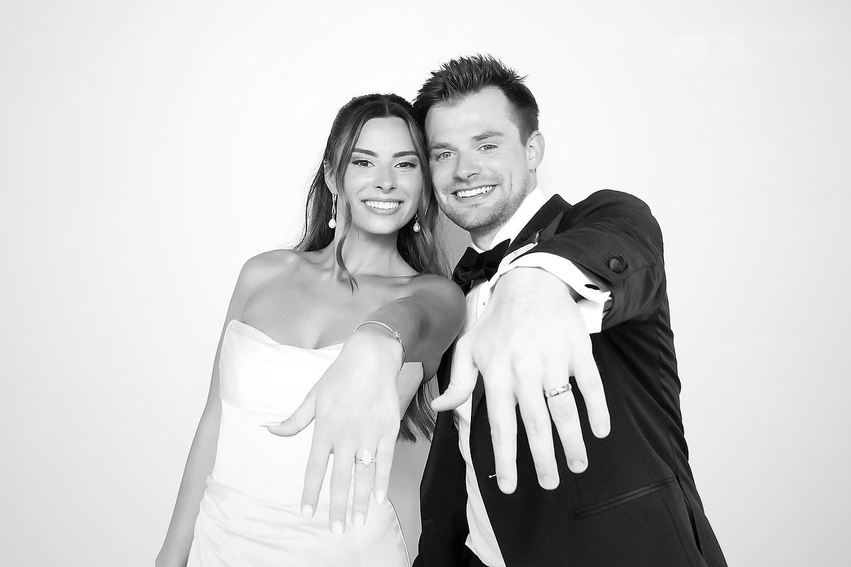 Bride and groom showing off their wedding rings in a black and white glam photo booth