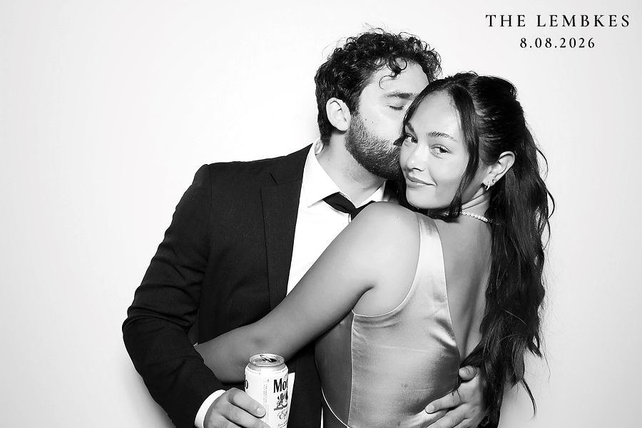 Groom and bride sharing a sweet moment in a black and white glam photo booth at a wedding