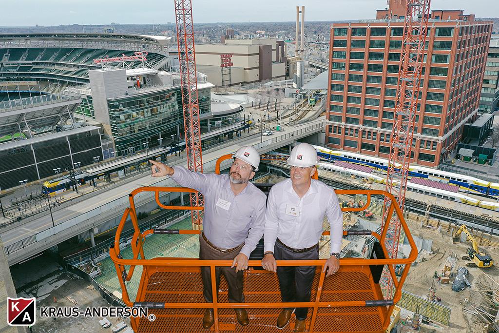 Immersive green screen photo of two guests in hard hats on a lift high above downtown Minneapolis