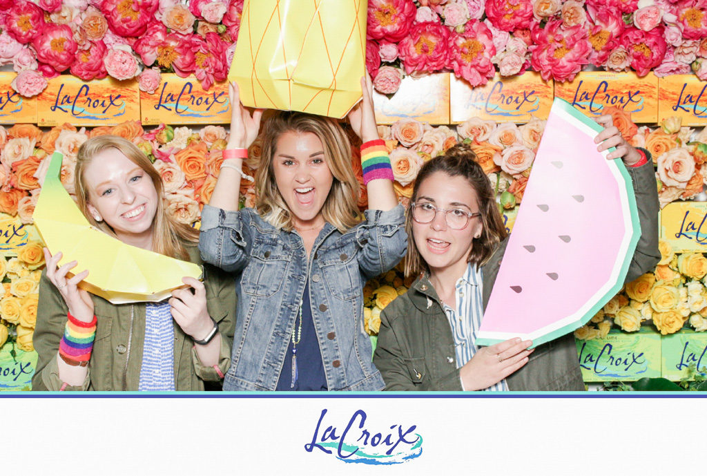 LaCroix brand activation print of three friends with giant fruit props in front of a flower wall