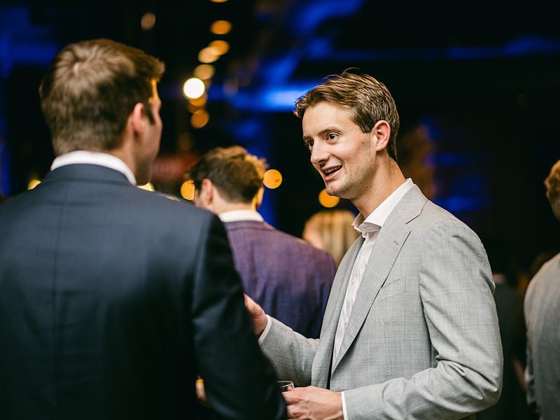 Two guests in suits talking at a networking reception