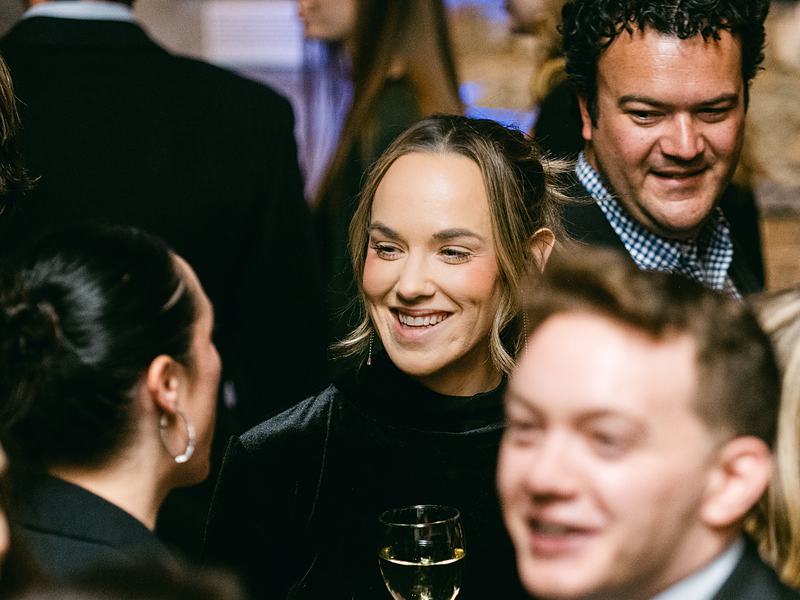 Coworkers laughing with wine glasses at a company holiday party