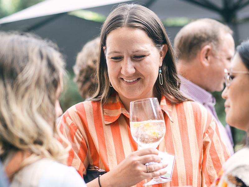 Guest laughing with a glass of wine at an outdoor garden reception
