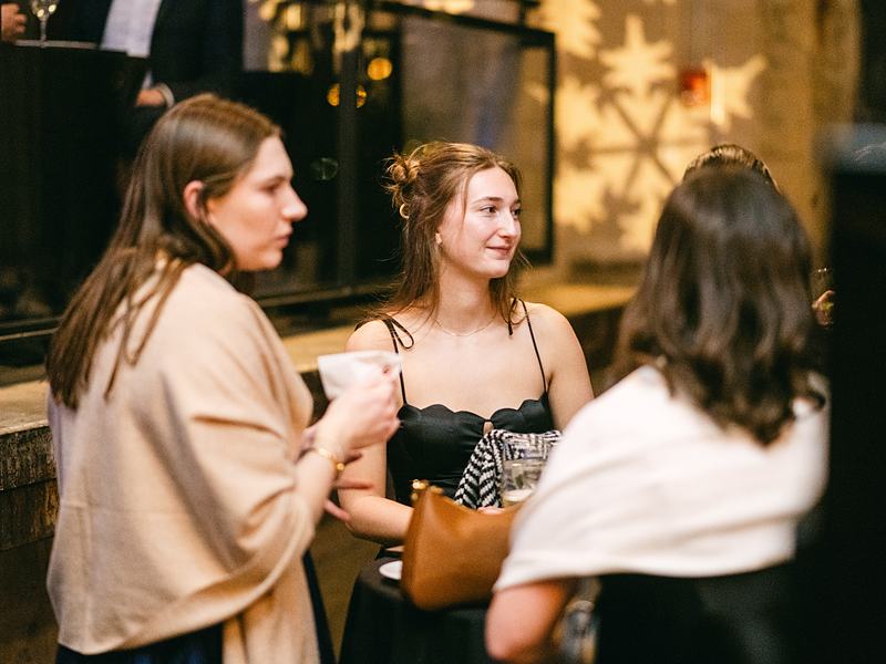 Guests chatting in winter coats at an evening reception