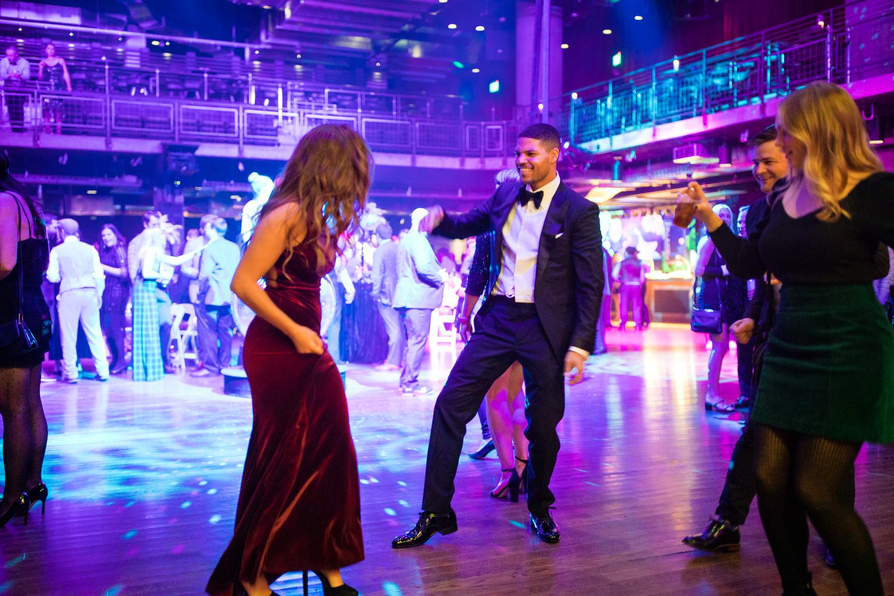 Guests dancing under blue and pink lights on a crowded dance floor at a corporate party