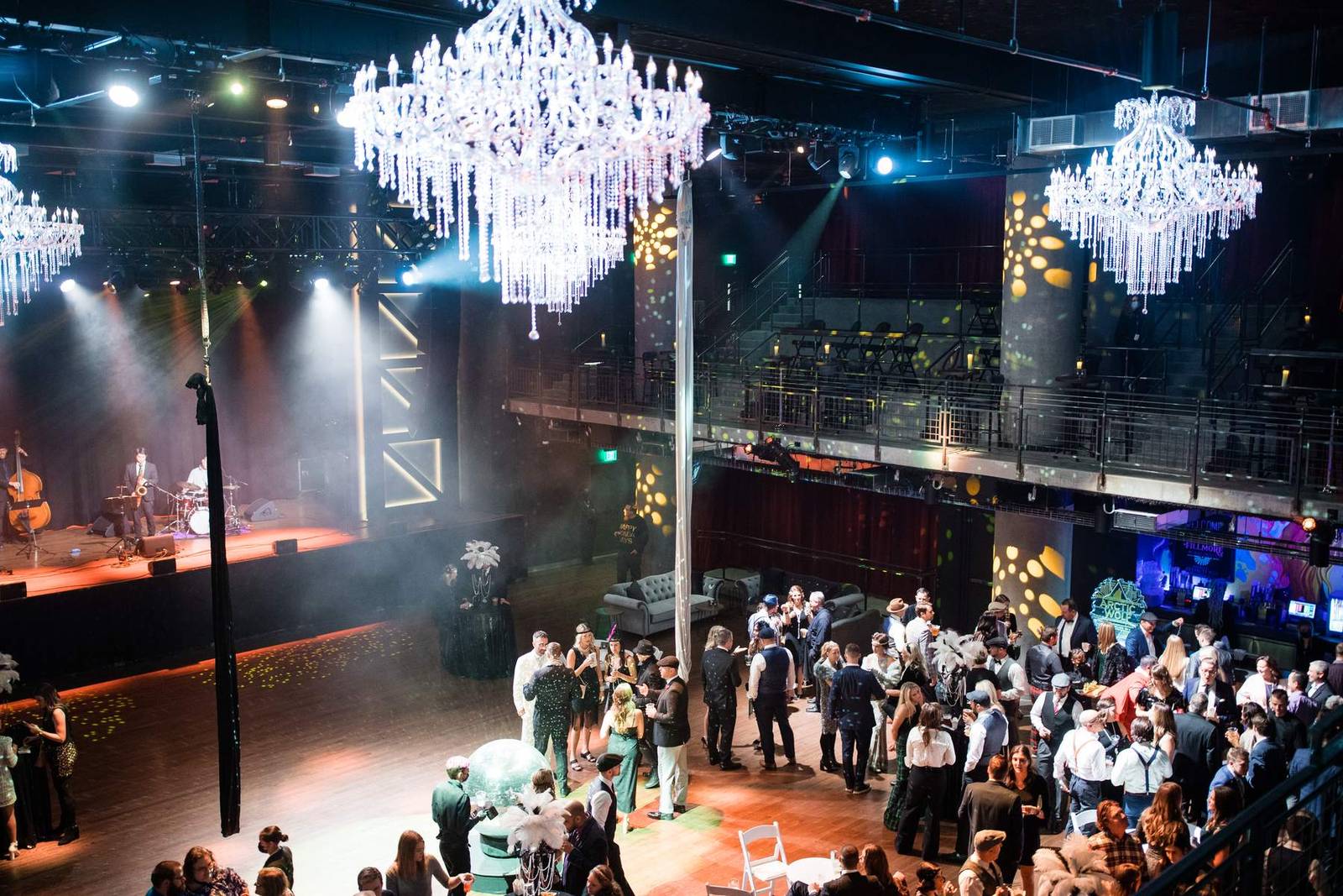 Packed Minneapolis event venue with crystal chandeliers and a live band, photographed from the balcony