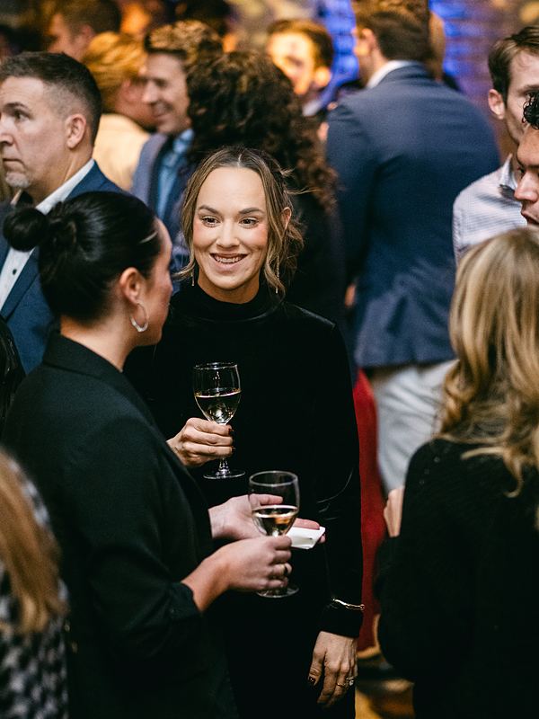 Guests toasting and laughing in a crowded room at a corporate holiday party